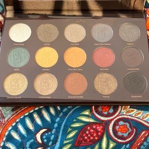 Ipsy bag with eyeshadow palette with two eye brushes and a lipstick.